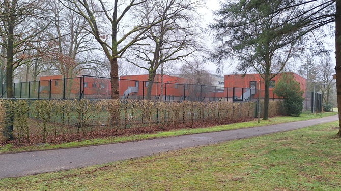 De behandelkliniek van Fivoor in Den Dolder: een rood gebouw met een hoog hek er om heen