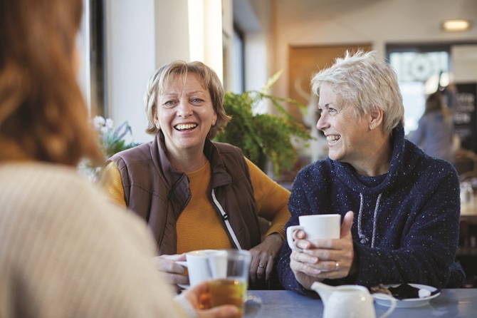 Ouderen zitten gezellig aan een tafel met een kop koffie na te praten na het voorleescafé in de bibliotheek van Zeis