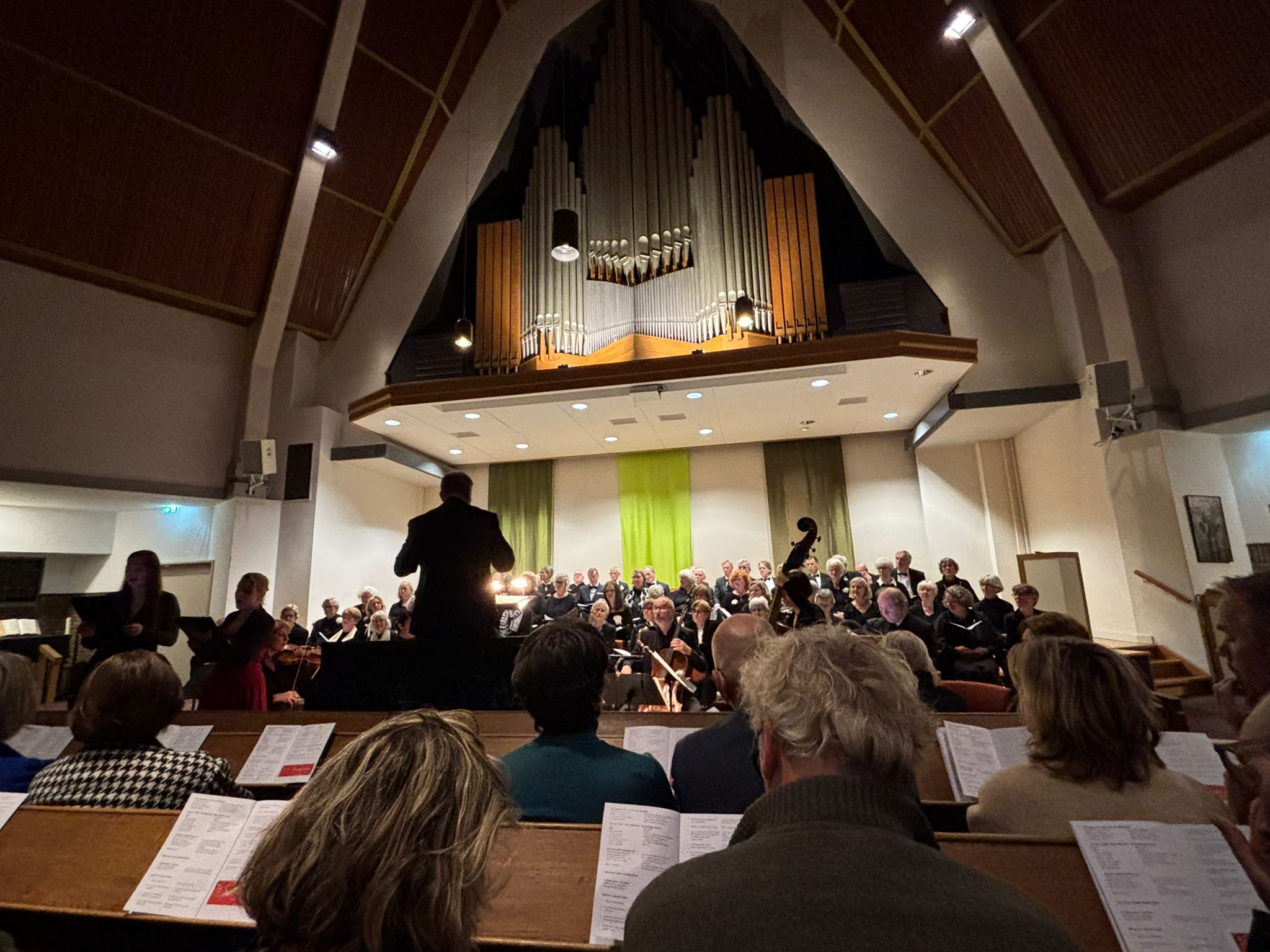 Het Toonkunstkoor Zeist zingt in de Oosterkerk, onder het hoge orgel, met de dirigent op de rug gezien