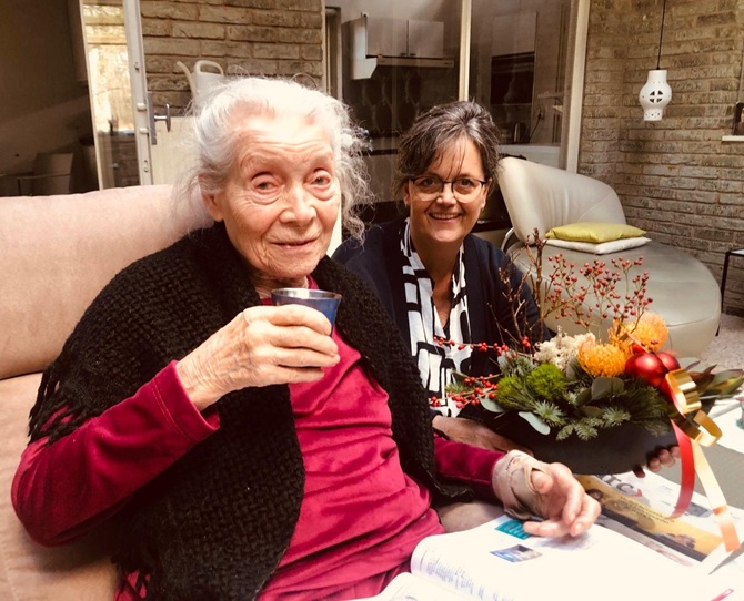 Twee oudere dames zitten op de bank en drinken een glaasje