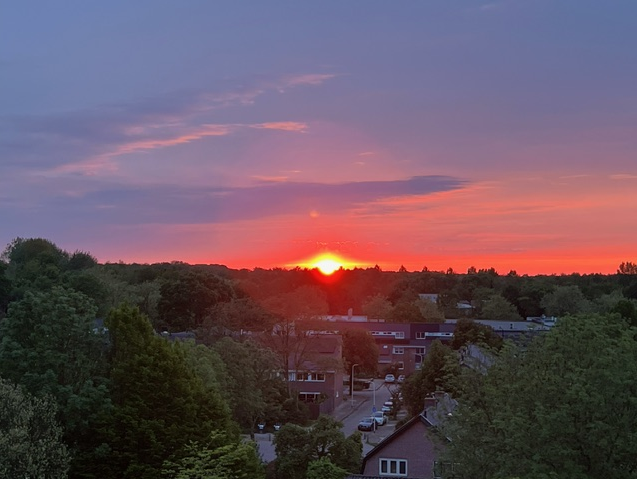 De lucht kleurt rood van de zonsondergang, gezien vanaf Flat 70 in Zeist