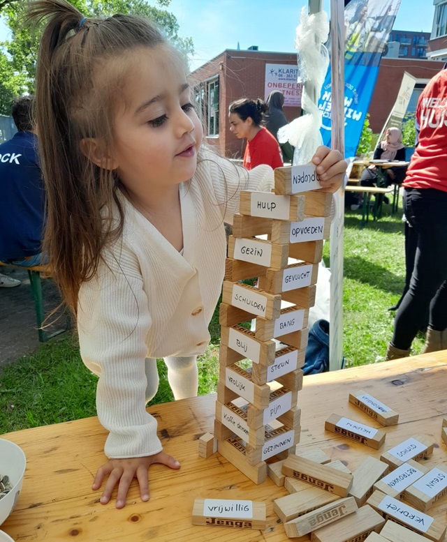 Een jonge vluchteling speelt met een stapel blokjes waarop woorden staan over asiel en opvang.