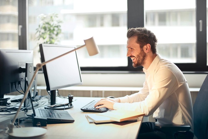 Een man zit aan zijn bureau achter de computer te werken