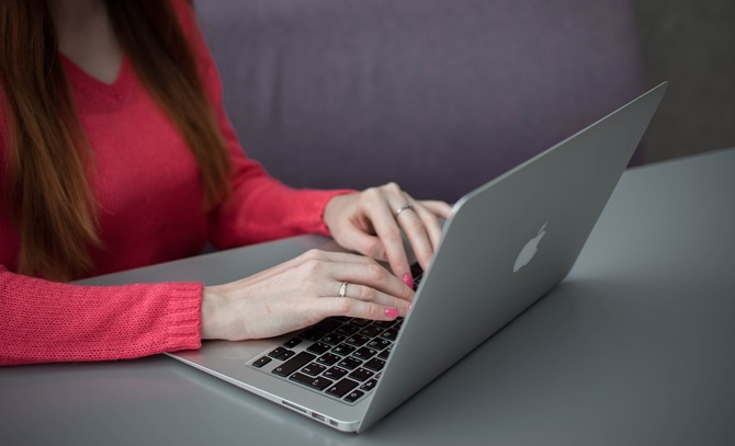 vrouw in rode trui achter een laptop