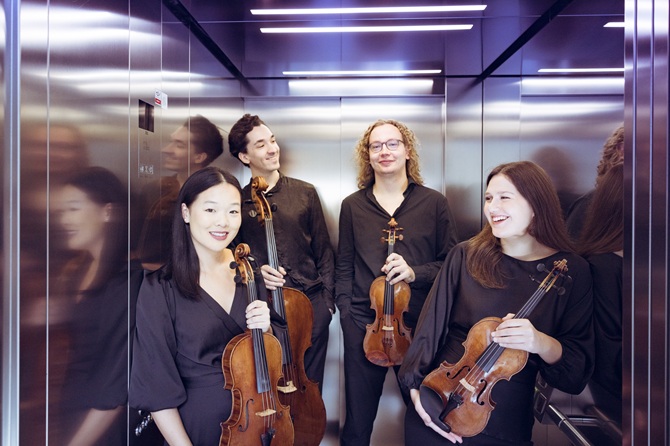 De vier leden van het Motus Quartet staan met hun viool in een lift. Ze treden op tijdens het Herfstconcert van de Zeister Muziekdagen.