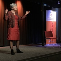 Een vertelster vertelt met brede armgebaren een verhaal tijdens het Vertelcafé in het Torenlaan Theater in Zeist