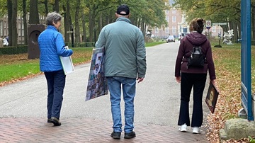 Drie leden van schildervereniging De Toets lopen met hun schilderij in de hand naar Slot Zeist voor de expositie