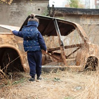 Meisje staat bij een uitgebrande auto in Armenië