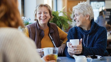 Vrouwen met een kop koffie aan een tafel praten na tijdens het Voorleescafé in de Bibliotheek van Zeist