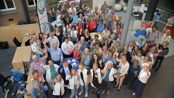 grote groep mensen zwaait vrolijk naar de fotograaf