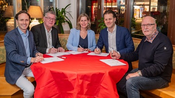 De prestatieafspraken voor Zeist 2025 worden ondertekend aan een ronde tafel met een felrood tafelkleed