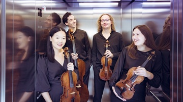 De vier leden van het Quartet dat optreedt tijdens het herfstconcert van de Zeister Muziekdagen staan met hun viool in een lift